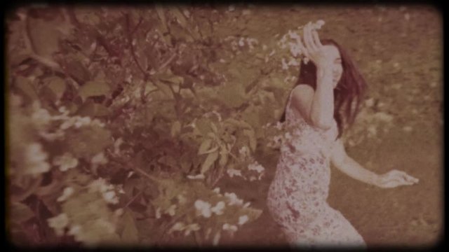 Family video archive. Retro camera 8&nbsp;mm. Old film. Young attractive woman having fun in the green garden. Portrait of a smiling brunette with dimpled cheeks against a green park. Pretty girl in summer