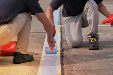 Two painters painting parking lots blue lines striping in a car park. © Nudphon