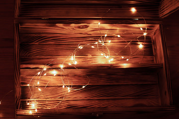 Magic box. Vintage wooden luxury gift box or casket on wood background. Open box filled with led garland
