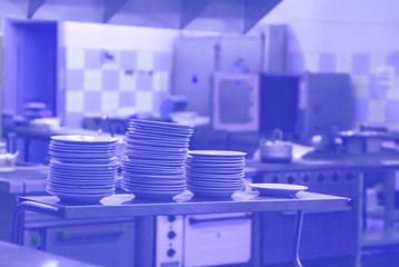 Fototapeta premium interior of the kitchen, a stack of clean plates in the kitchen are on the tables. in the background of the stove