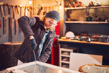 Woman carpenter sanding old window in a retro workshop.