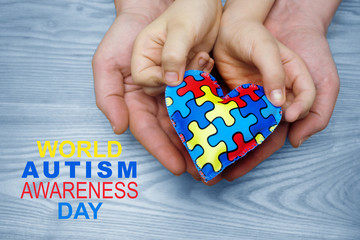 World Autism Awareness day, puzzle or jigsaw pattern on heart with autistic child's and father hands