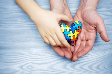 World Autism Awareness day, puzzle or jigsaw pattern on heart with autistic child's and father hands