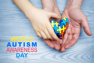 World Autism Awareness day, puzzle or jigsaw pattern on heart with autistic child's and father hands