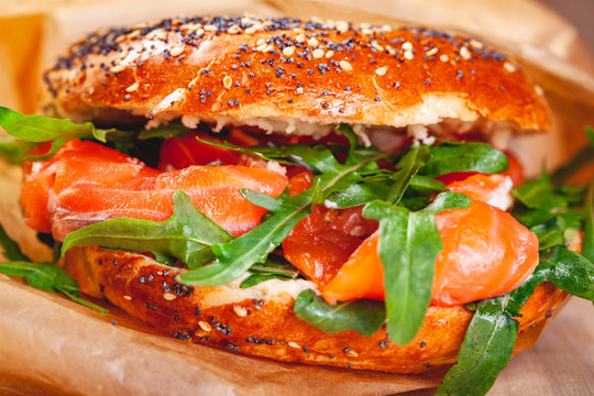 Bagel with cream cheese, smoked salmon and arugula salad in brown paper bag. Close up