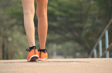Closeup female walking with orange shoes on road in park for health concept