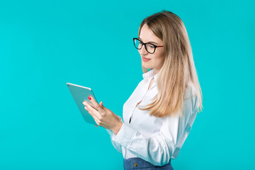 Portrait young caucasian woman worker teacher trainer mentoring in white shirt office style long hair with a tablet in hand uses technology isolated bright color blue background