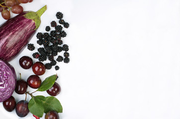 Raw violet vegetables and fruit on white background.