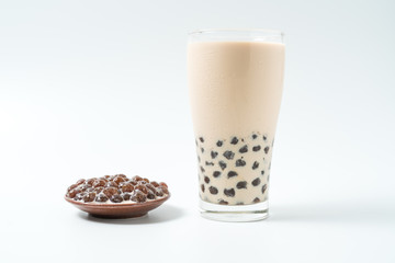A glass cup of pearl milk tea (also called bubble tea) and a plate of tapioca ball on white background. Pearl milk tea is the most representative drink in Taiwan. Taiwan food . With copy space.
