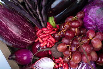 Raw violet vegetables and fruit on white background.