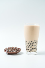 A glass cup of pearl milk tea (also called bubble tea) and a plate of tapioca ball on white background. Pearl milk tea is the most representative drink in Taiwan. Taiwan food . With copy space.