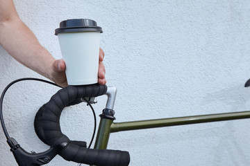 Young man with disposable coffee cup and bike