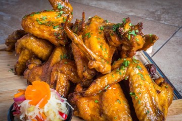 Buffalo chicken wings with  sweet chili sauce on white wooden board