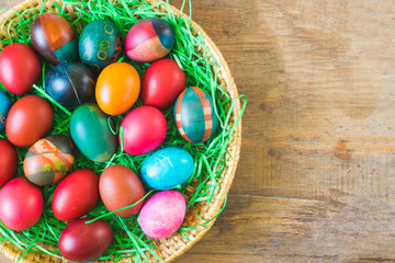 Fototapeta na wymiar Colorful Easter eggs in basket on old wooden background