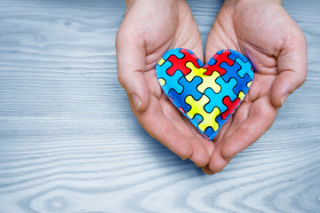 World Autism Awareness day, puzzle or jigsaw pattern on heart with father hands