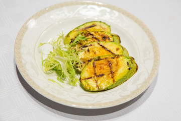 delicious fried zucchini grilled beautifully served on a platter in the restaurant,.fried zucchini in oil on a plate close-up, zucchini with toasted crust and salad on a dish