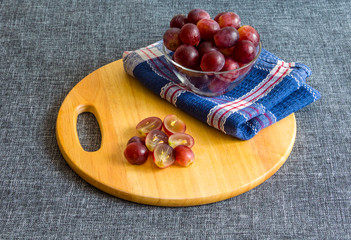 Large grapes in a glass bowl, chopped grapes. On a wooden cutting board