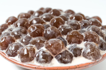 A glass cup of pearl milk tea (also called bubble tea) and a plate of tapioca ball on white background. Pearl milk tea is the most representative drink in Taiwan. Taiwan food . With copy space.