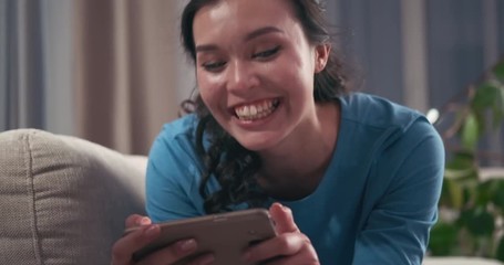 Woman laughing while watching online media content on mobile phone at home