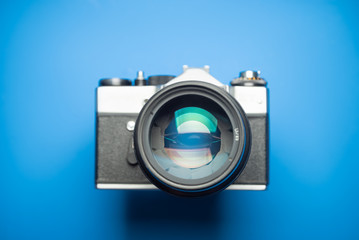 An old vintage camera. Focus on lens aperture. Blue background