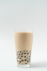 A glass cup of pearl milk tea (also called bubble tea) and a plate of tapioca ball on white background. Pearl milk tea is the most representative drink in Taiwan. Taiwan food . With copy space.