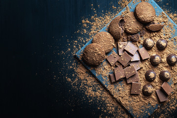 Chocolate chip cookies, broken pieces of chocolate and cocoa powder on a wooden background...