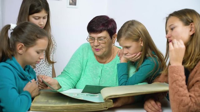 Grandmother showing old photo album to her four granddaughters