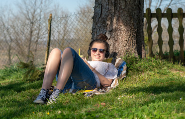 teenager girl listening music and drinking water in the park