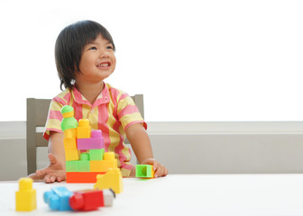 Kid playing with colorful toy blocks. Little boy building tower of block toys. Educational and creative toys and games for young children. Baby in white bedroom with rainbow bricks. Child at home