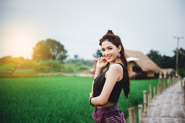 Beautiful Asian woman in local dress standing and enjoy natural on bamboo bridge in rice field