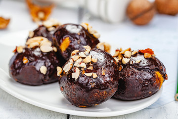 Cookie balls with chocolate glaze and walnuts on white plate. Close up