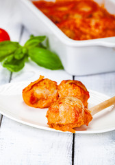Meatballs with tomato and sour cream sauce on white plate. Close up