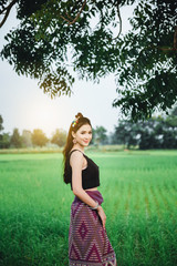 Obraz premium Beautiful Asian woman in local dress standing and enjoy natural on bamboo bridge in rice field