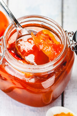 Persimmon jam in glass jar on wooden  background. Close up