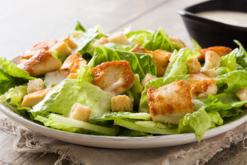 Caesar salad with lettuce,chicken and croutons on wooden table.. Close up