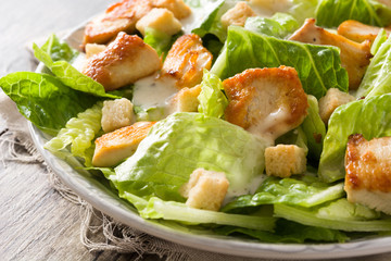 Caesar salad with lettuce,chicken and croutons on wooden table.. Close up