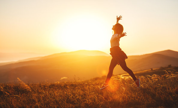 Happy Woman Jumping And Enjoying Life  At Sunset In Mountains.