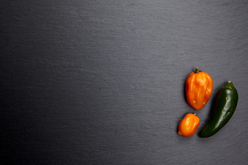 Bunte Chili Schoten auf dunkler Steinplatte