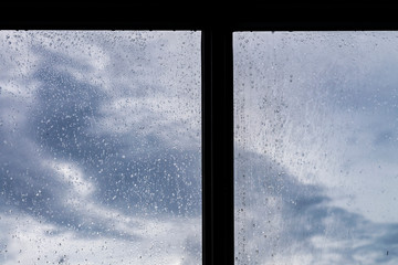 Rain / Water drop of rain on glass with blue sky and cloudy outdoor background