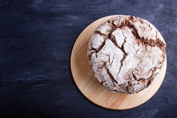 Yeast free homemade bread with whole rye and wheat grains on black wooden background.