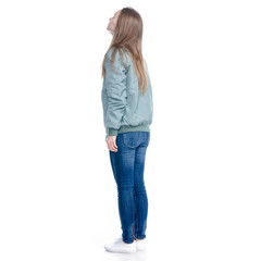Woman in jeans and green jacket standing looking on white background isolation, back view