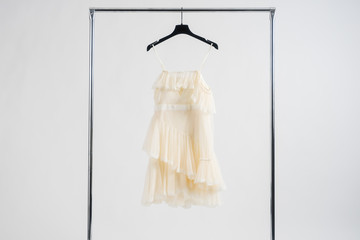 Beautiful white short wedding dress hanging on dressing rail. White background with copy space.