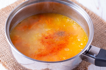 Pumpkin soup in a pan with spices on the table