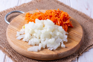 Onions and carrots chopped on a cutting board on a wooden table