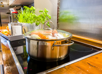 Chicken soup cooking in a pot on ceramic glas cooktop