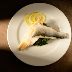 Roasted fish filet decorated with lemon slices on a plate