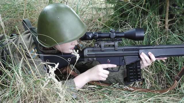 Close Female soldier in meadow aims target and duck