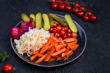 Different types of pickled vegetables on a dark background
