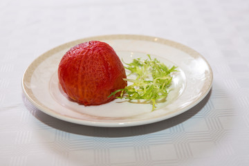 delicious whole big tomato without skin grilled beautifully served on a platter in the restaurant,.fried red tomato in oil and own juice on a plate close-up, tomato and salad on a dish