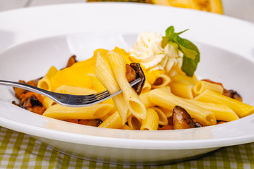 Penne pasta with pumpkin, tofu and mushrooms on white plate. Close up